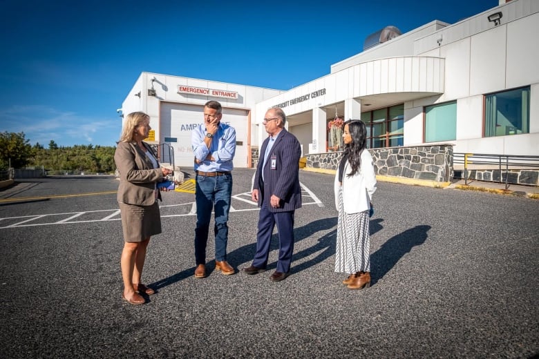 Four people stand outside of a hospital.