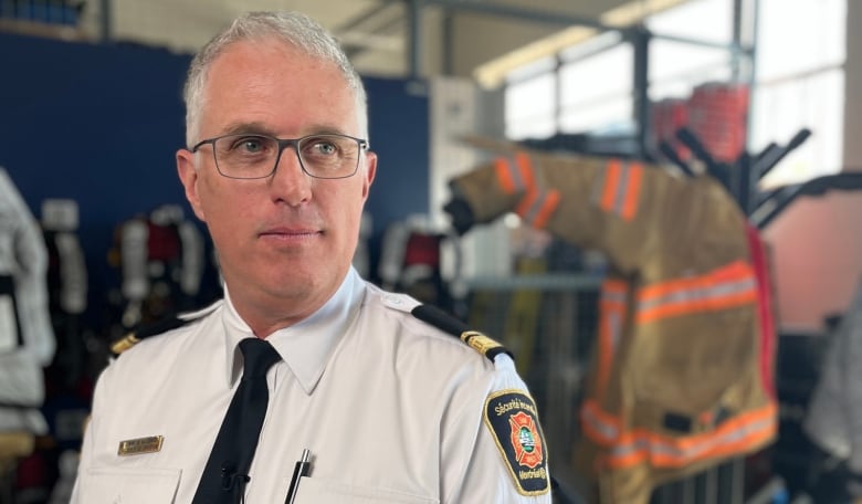 A man wears a uniform in a fire hall.