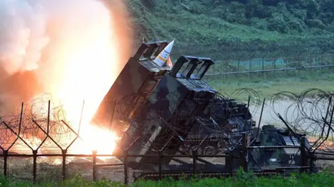 Getty Images ATACMS missiles are seen during South Korea-US military exercises, surrounded by barbed wire fencing and lush greenery in the background. 