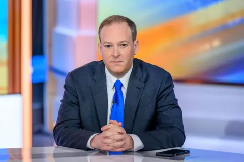 Getty Images Man sits with his hands folded while wearing a blue tie