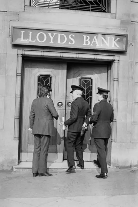 Getty Images Black and white archive image, showing Lloyds Bank and detectives and uniformed officers entering the bank 