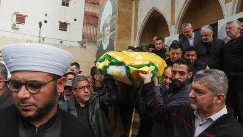 Reuters Mourners carry the body of Hezbollah's spokesman Mohammed Afif, who was killed by an Israeli strike on a building in central Beirut, during his funeral in Sidon, southern Lebanon (18 November 2024)