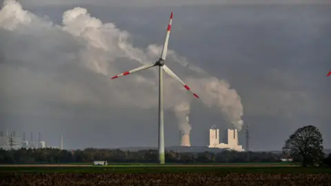 Getty Images Wind turbine with power station in background