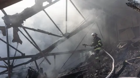 Getty Images Ukrainian emergency service workers extinguish a fire in a factory after a Russian shelling as the Russia-Ukraine war continues in Kostiantinivka, Ukraine.