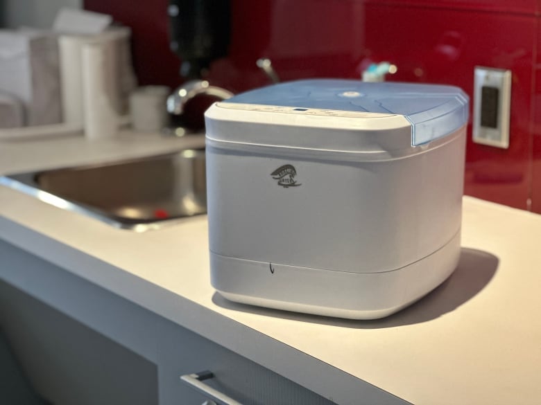 A machine sits on a kitchen counter. It is white and square-ish.