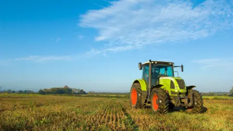 Getty Images A farmer driving a tractor in the UK. 