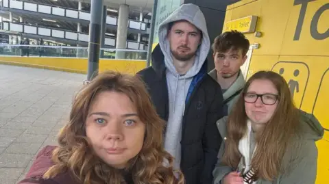 Emily Fisher Four young people, two boys two girls, stood at Gatwick Airport for a selfie