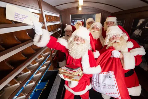 Matt Alexander/PA Media Men dressed as Father Christmas post letters