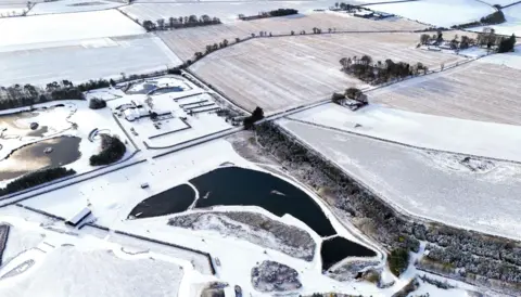 Jane Barlow/PA Media Fish-shaped Muckle Troot Loch is seen from above surrounded by snow and ice