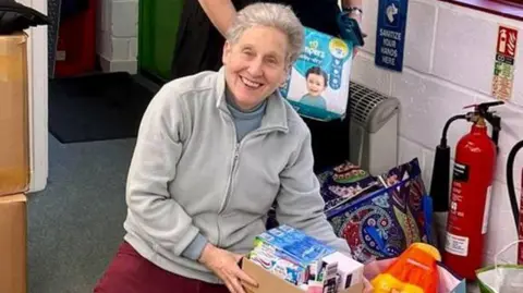 Jenny Jenny kneeling on the floor packing Christmas parcels at a charity