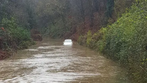 Ini A car is stuck on a flooded road.