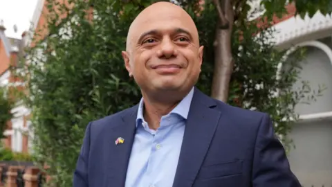 Reuters Sajid Javid pictured leaving his home in London, July 6, 2022, seen with trees and houses in the background