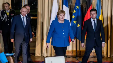 Getty Images Angela Merkel walks towards the camera alongside Vladimir Putin and Volodymyr Zelensky at a meeting in Paris in 2019