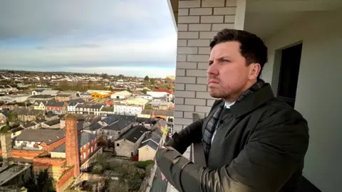 Martin Loughran is standing on a balcony and looking out over an urban landscape