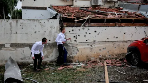 Reuters Boys walk at the scene of a Hezbollah rocket attack in Petah Tikva, Israel (24 November 2024)