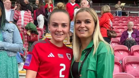 Tara Male Lily Woodham stands in a Wales football shirt with her friend at a game