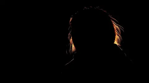 The outline of a woman against a black background. 