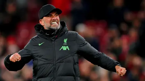 PA Media Jurgen Klopp in Liverpool FC matchday attire and trademark baseball cap, punching the air