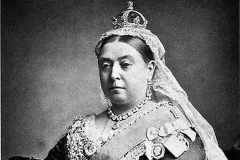 Alamy Black and white picture of Queen Victoria. She is wearing a crown with a veil hanging down from the back of it. She is wearing a thick necklace and a v-necked dress.