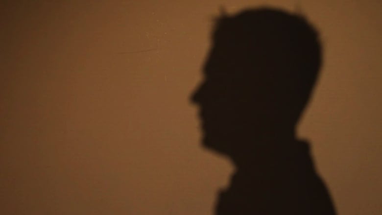 The silhouette of a man is shown against a wall.