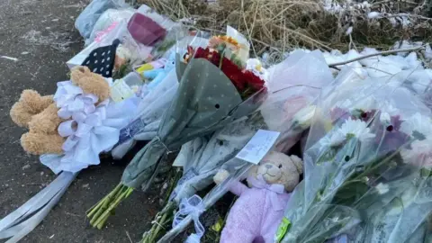 BBC Flowers, teddy bears and tributes left on the ground at the scene where the baby remains were found