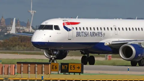 Getty Images A British Airways plane sits on the runway in Barcelona, with signs on the ground and buildings in the background