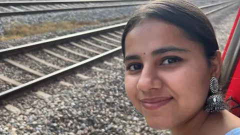 Family Harshita Brella stares into the camera with train tracks in the background