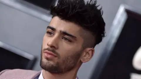 Getty Images Zayn Malik attending the 60th Annual GRAMMY Awards at Madison Square Garden - he has his hair spiked up with a nose ring, and has a neutral expression on his face. 