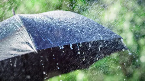 Getty Images/Brian A Jackson Heavy rain falling on a black umbrella