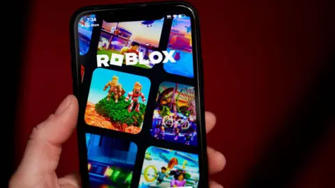 Getty Images Roblox displayed on a smartphone in a close-up shot of a person's hand