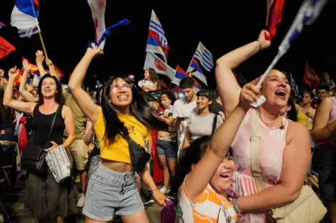 Andres Cuenca/Reuters Supporters of Yamandu Orsi, centre-left presidential candidate, celebrate following early results in Uruguay's presidential election run-off 