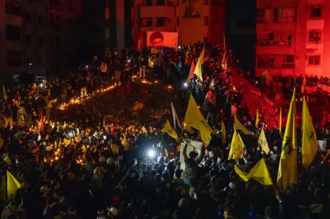 Joel Gunter/BBC Crowds surged into the area and climbed around the crater, chanting Nasrallah's name. 