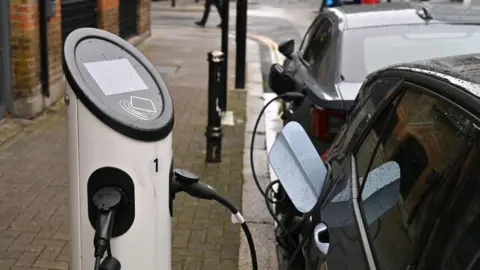 Getty Images Cars parked on a street using a public charging point