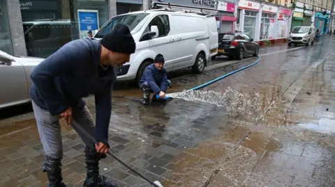 Getty Images Two men clearing flood water on Mill Street in February 2020