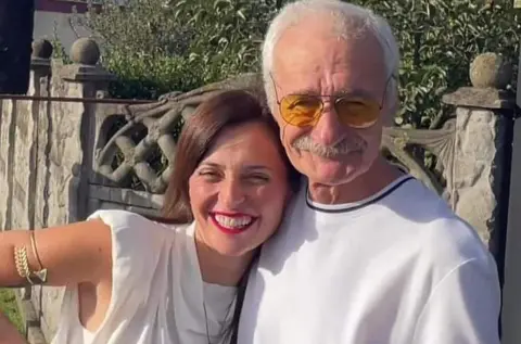 Tamuna Museridze Tamuna with her father Gurgen. They are both smiling and are standing close together - she has her head on his shoulder. She has long, straight, dark hair and is wearing a sleeveless, white top. He has white hair and a moustache. He is wearing glasses and a white top.