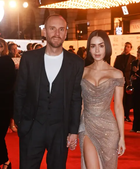 Alan Chapman/Dave Benett/Getty Images Charlie McDowell (left) and Lily Collins hold hands on Devil Wears Prada The Musical red carpet