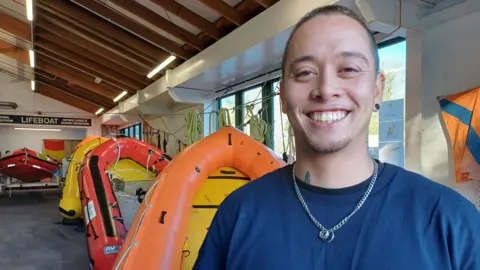 Theo Tran, a search and rescue Instructor with the charity is pictured next to rigid-hulled inflatable boats used in search and rescue operations 