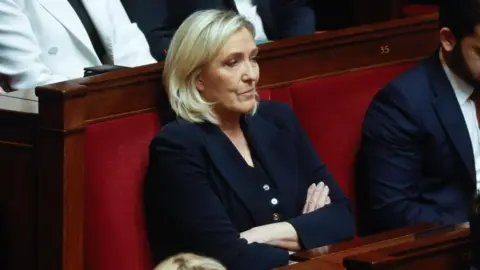 EPA Marine Le Pen sits with her arms folded as she watches on in the French National Assembly debate