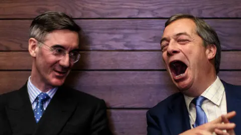 Getty Images Jacob Rees-Mogg and Nigel Farage. Rees-Mogg is wearing glasses, shirt and tie and is turning his face to the right. Farage is wearing a dark suit, checked shirt and blue tie and is laughing out loud