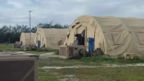 Supplied Three large tents stand in a row on grassland on Diego Garcia