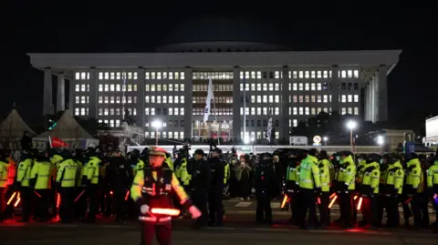 Reuters Dozens of police officers in yellow hi vis jackets gather outside the National Assembly in Seoul 