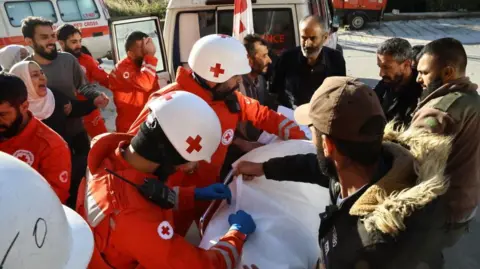 Getty Images Relatives of a person who died in an attack carried out by the Israeli army in the town of Shebaa in southern Lebanon mourn as the person lies on a stretcher surrounding by medical workers in orange uniforms