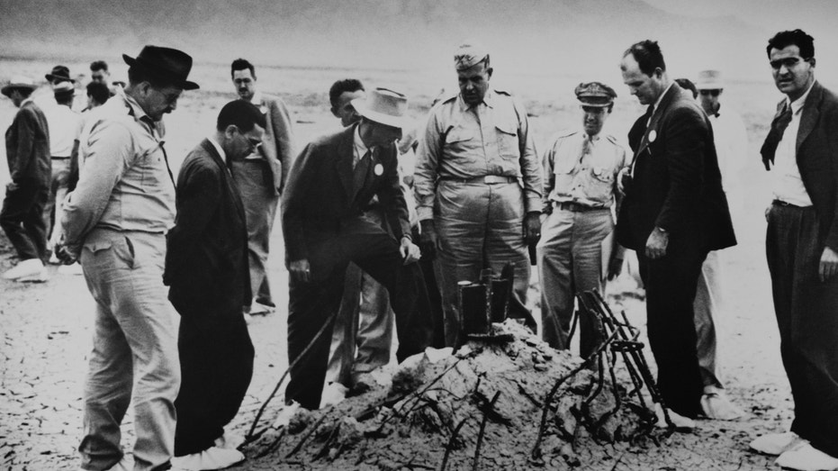 Robert Oppenheimer and General Leslie Groves (center) examine the twisted wreckage that is all that remains of a hundred-foot tower, winch, and shack that held the first nuclear weapon. On the far right is Victor Weisskopf, of the Manhattan Project's Theoretical Division.