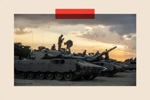 Getty Images Soldiers stand on top of military tanks and armoured vehicles, as the sun begins to set in the background.