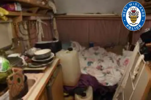 West Midlands Police The living conditions inside the caravan. Dishes are piled up on the side and a duvet and containers are situated in the middle 