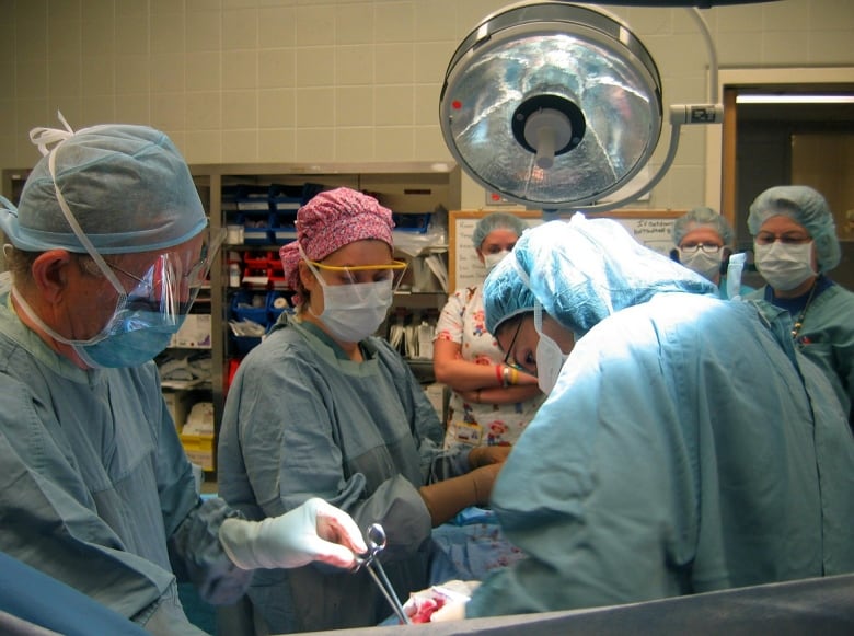 Operating room doctors and nurses perform a C-section delivery