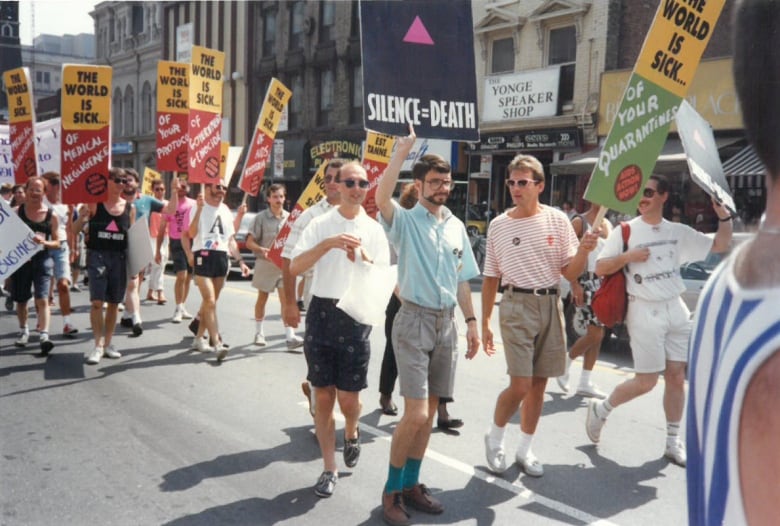 People are seen marching down a road, holding signs.