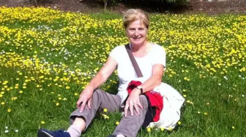 Wiltshire Police Danielle Carr-Gomm sitting in a grassy field with daffodils, smiling at the camera