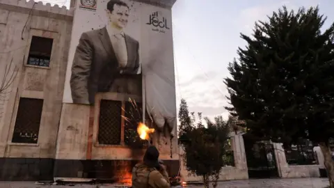 Getty Images A fighter firing at a poster of Assad