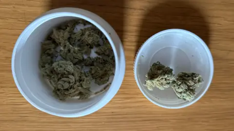 Cannabis flower in a pot and a lid on a table